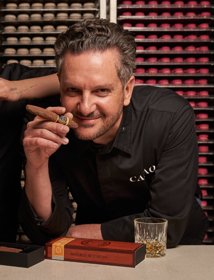 CACAO chocolatier holding a handcrafted dark chocolate cigar, with the Father's Day gift box on the table